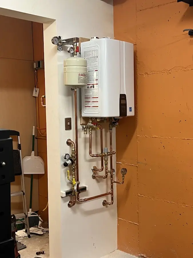 Plumbing technician inspecting water heater connections in East Milton